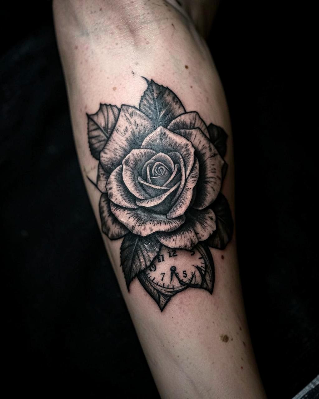 Black and grey rose and pocket watch tattoo on an inner forearm